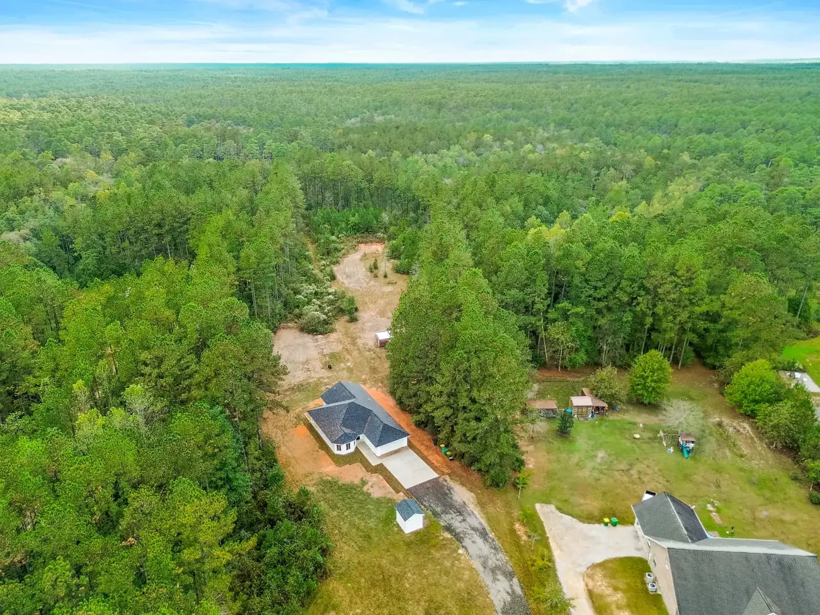Aerial view of a new custom home surrounded by pine forest, built by Supreme Contractors Group in Vancleave, Mississippi