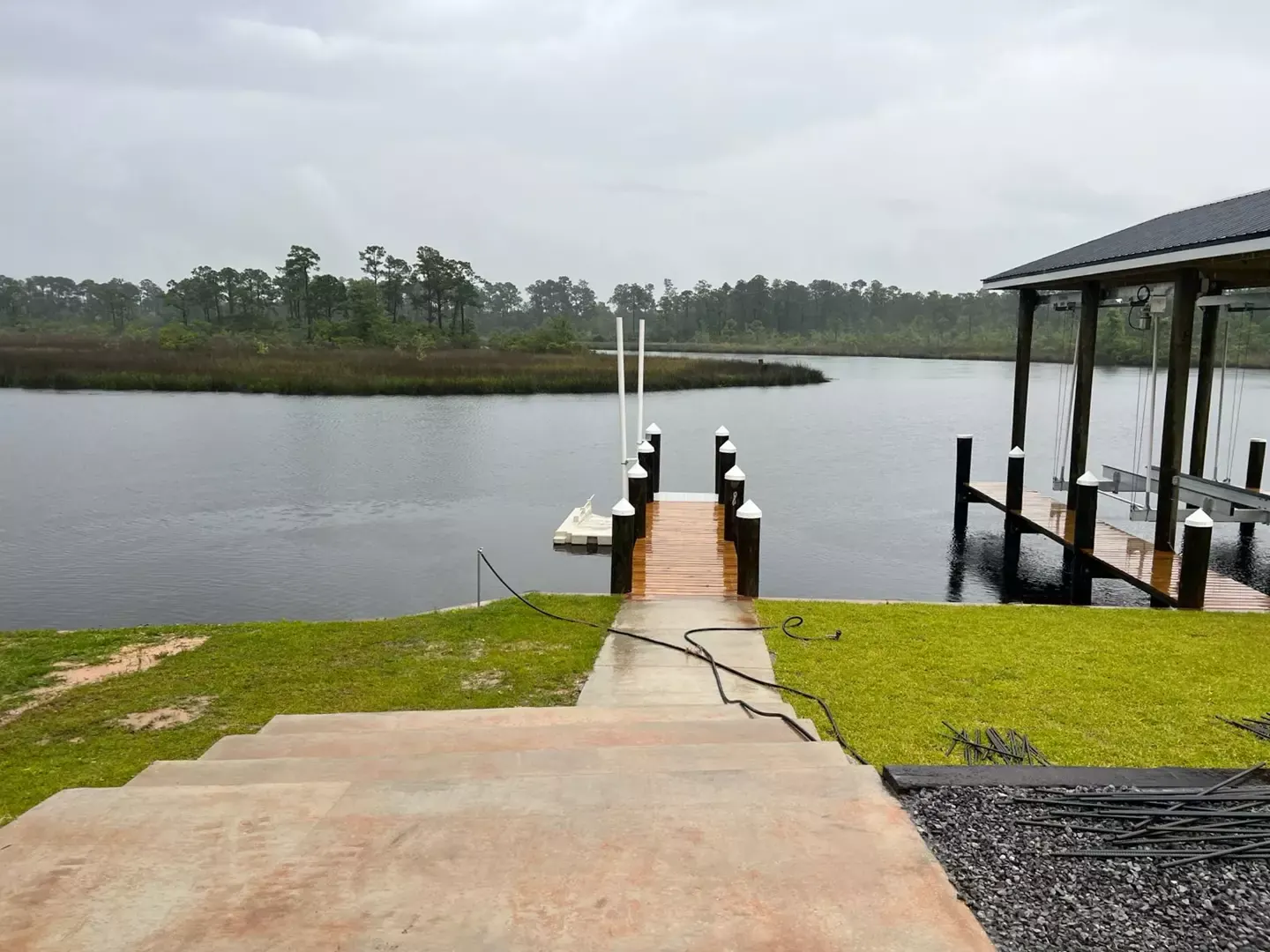 Private pier with a covered boat lift behind a waterfront modern farmhouse built by Supreme Contractors Group in Ocean Springs, Mississippi